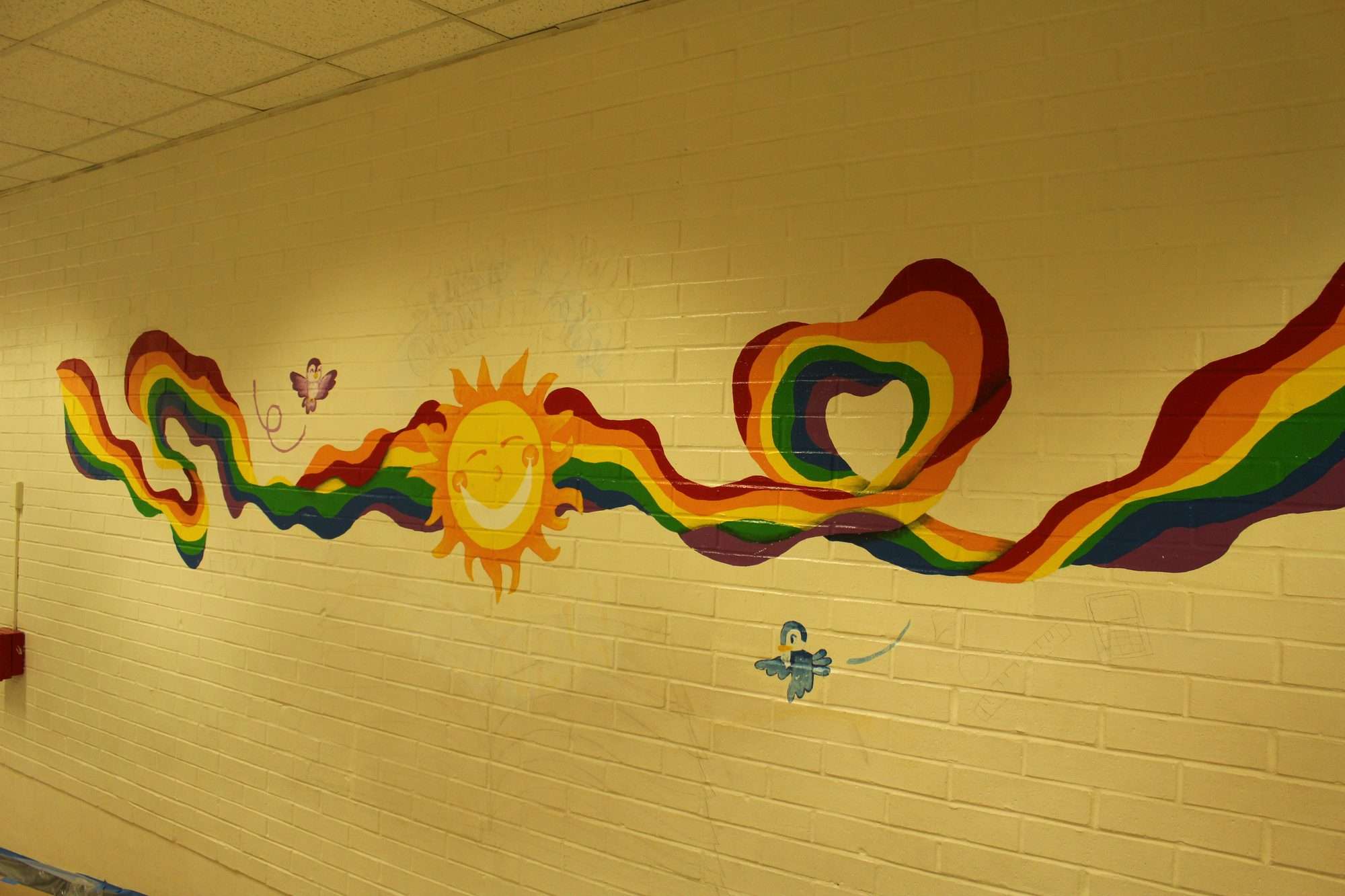 A smiling sun and a ribbon of rainbow colors stretching along a school corridor